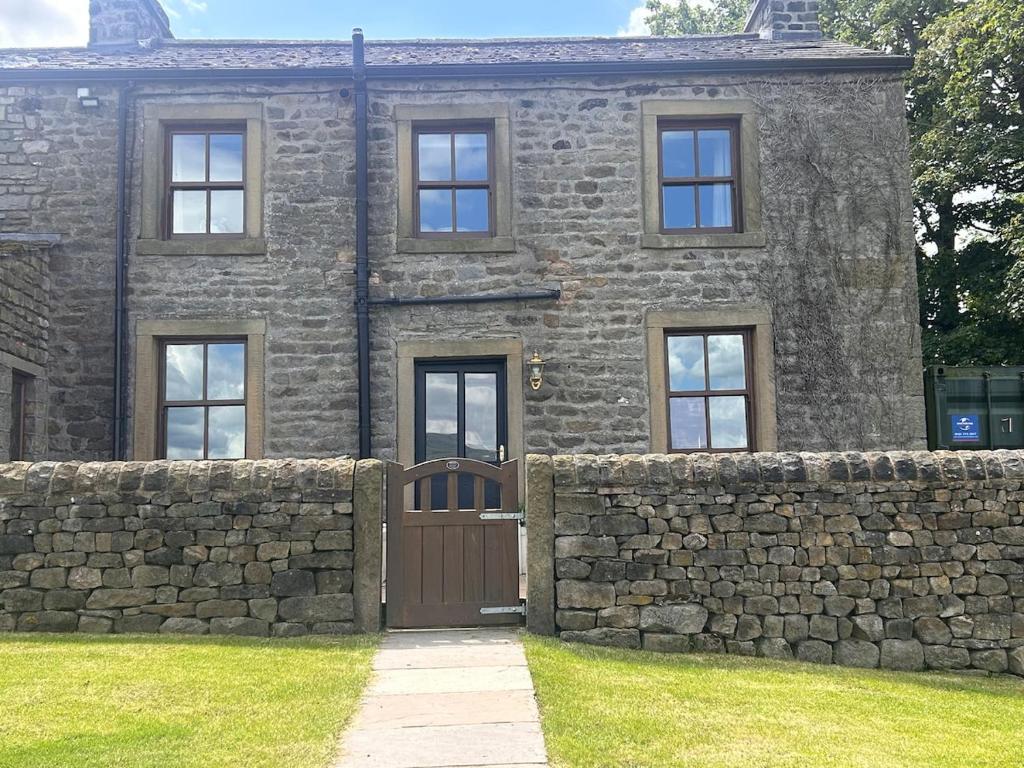 a stone house with a gate and a stone wall at Heigh Farmhouse in Lancaster