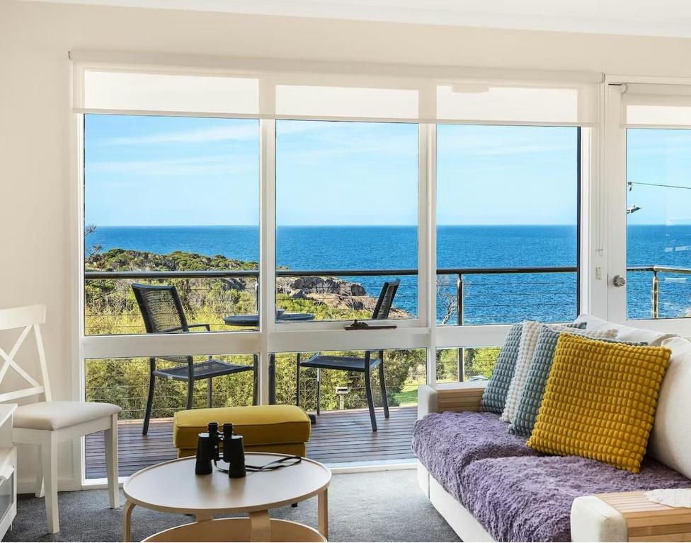 a living room with a couch and a view of the ocean at Whale Stay in Tathra