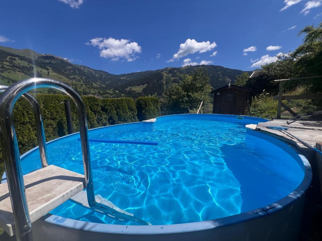 a swimming pool with blue water and mountains in the background at Patzberg Liesl in Dorfgastein