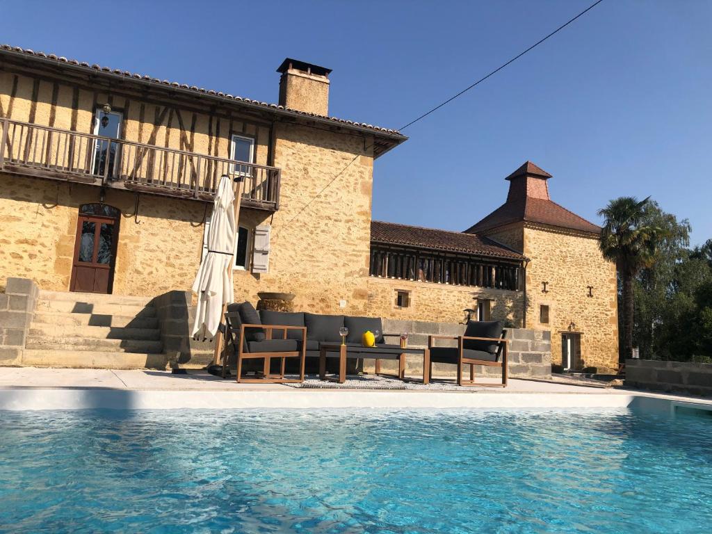 a patio with chairs and an umbrella next to a pool at Gîte La Carole 120m2 in Monlezun