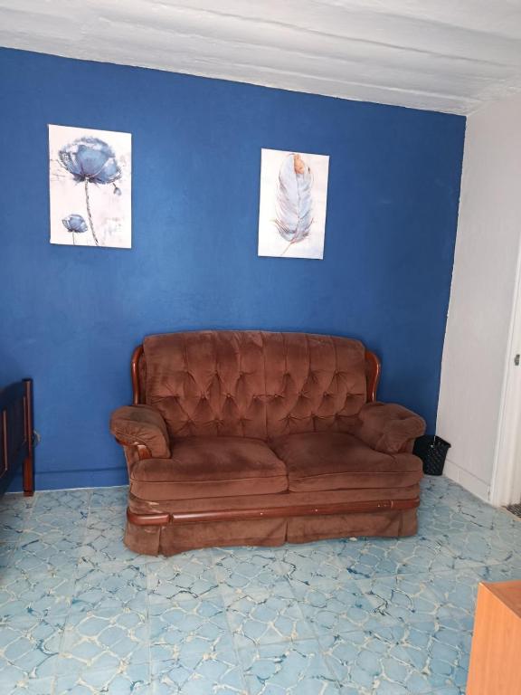 a living room with a brown leather couch against a blue wall at Studio Azul in Tlaxcala de Xicohténcatl