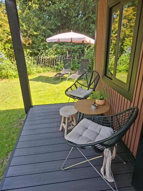 a porch with chairs and a table and an umbrella at 'De Schuif' in Berlicum