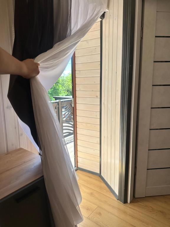 a person is holding a curtain in front of a door at Білий птаха in Svityazʼ