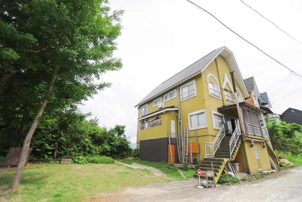 a yellow house with stairs on the side of it at Saunalodge 白道 in Minami Uonuma