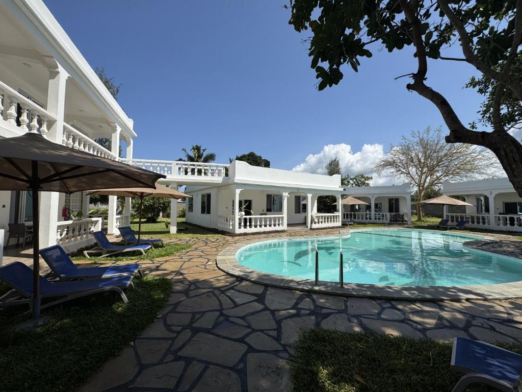 a large white house with a swimming pool at M&H Boutique Hotel in Mombasa