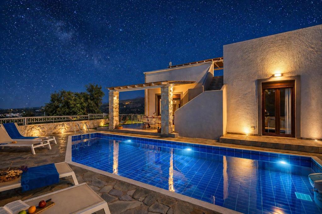 a villa with a swimming pool at night at Villa Ikaros in Agia Triada