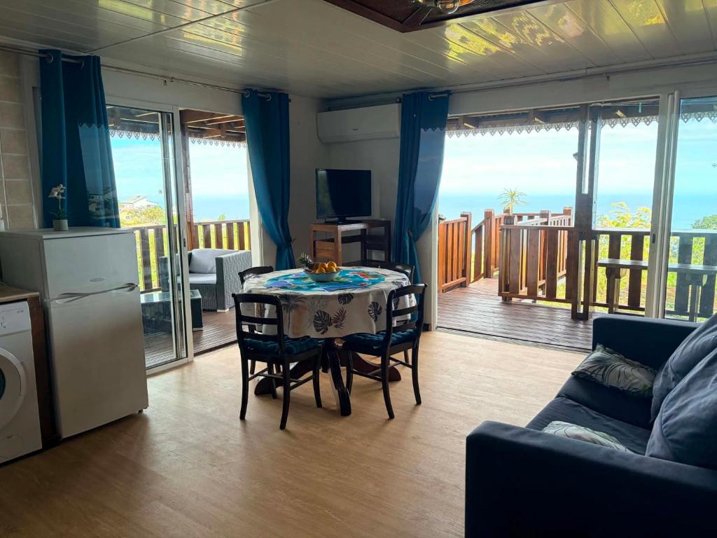 a living room with a table and chairs and a balcony at Le petit meublé des hauts in Grande Ravine