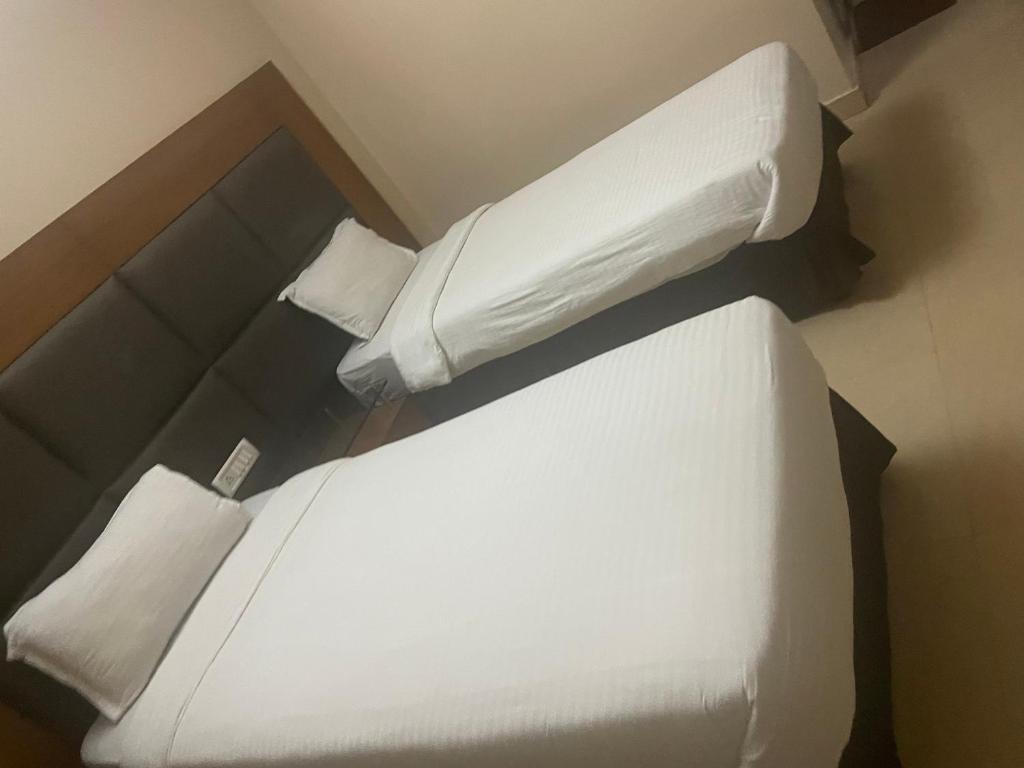 ein Schlafzimmer mit einem weißen Bett und zwei Kissen in der Unterkunft Hotel Damchen in Phuentsholing