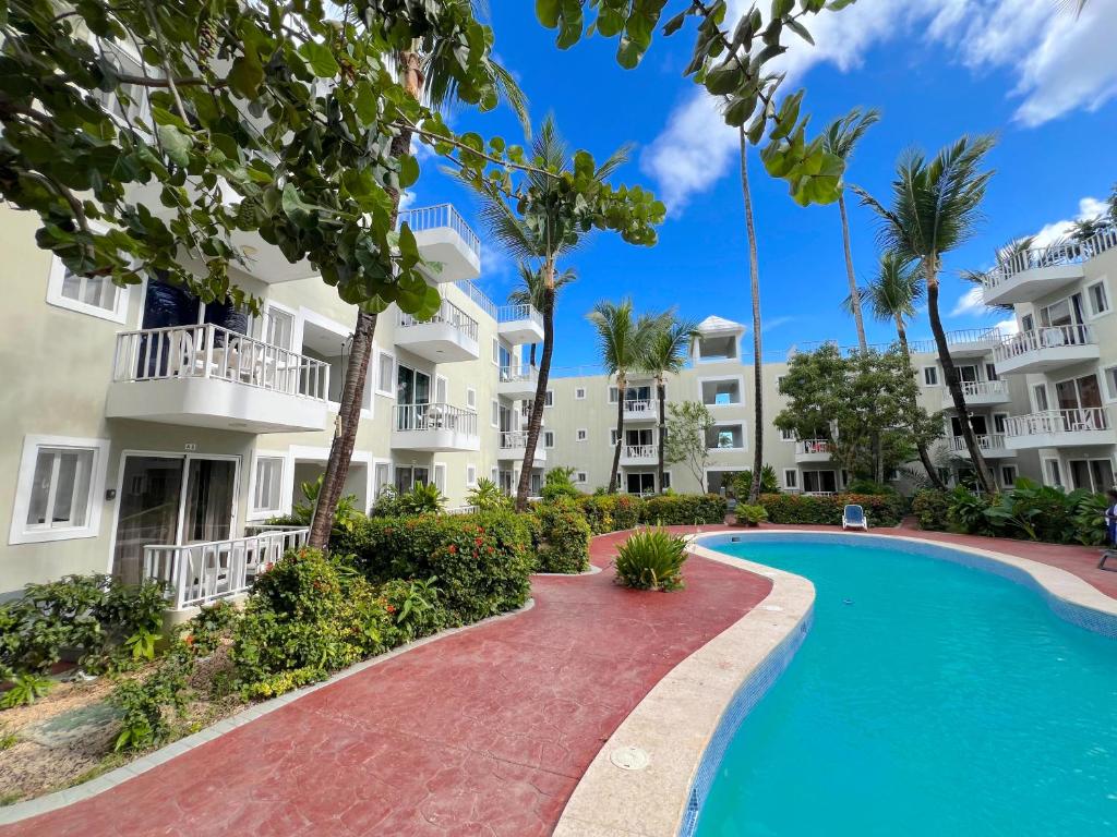 a swimming pool in front of a building at DELUXE STUDIOS with POOL VIEW and Wi-Fi at PLAYA LOS CORALLES in Punta Cana