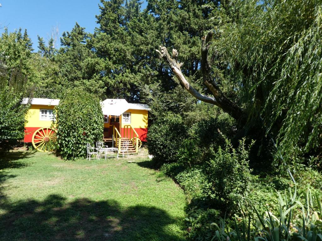 a yellow and red caravan in a yard with trees at La Roulotte in Arles