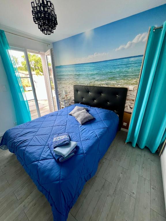 a bedroom with a blue bed with a view of the ocean at Chez Christelle in Audenge