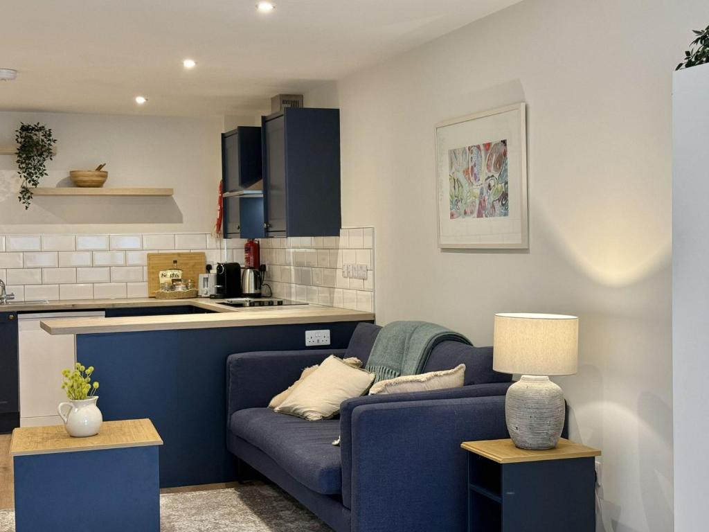 a living room with a blue couch and a kitchen at Apartment 299 - Clifden in Clifden