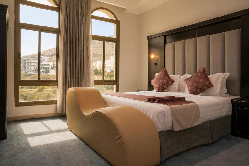 a bedroom with a large bed with a large window at Pherbion Hotel Apartment Abha in Abha
