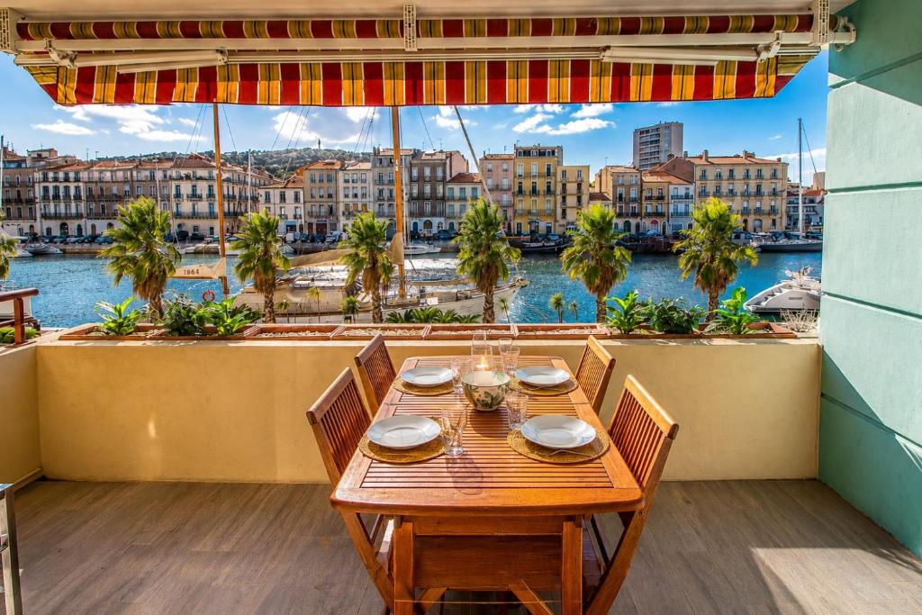a wooden table on a balcony with a view of the water at L'ariot 1984 - appartement cosy avec terrasse, parking et wifi in Sète