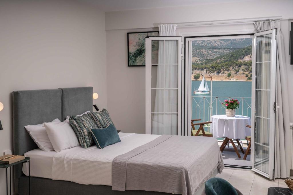 a bedroom with a bed and a balcony with a table at Argostοli Bay Apartments in Argostoli