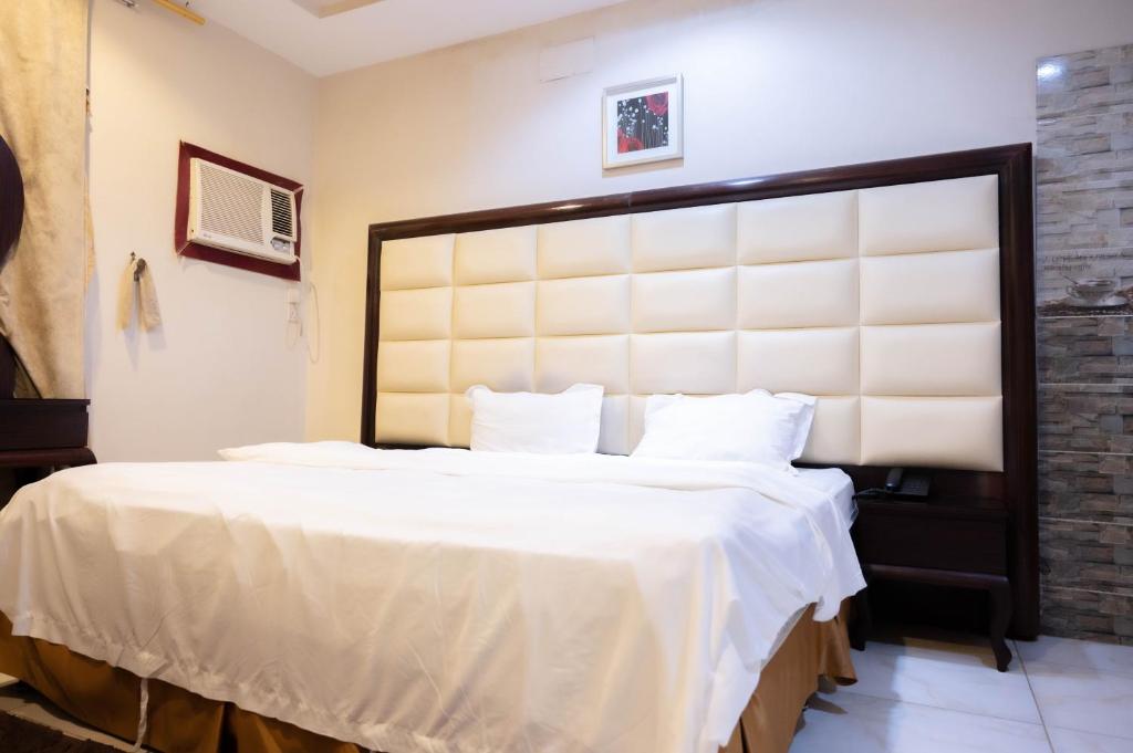 a bedroom with a large bed with white sheets at شقق القنفذة بلس in Al Qunfudhah