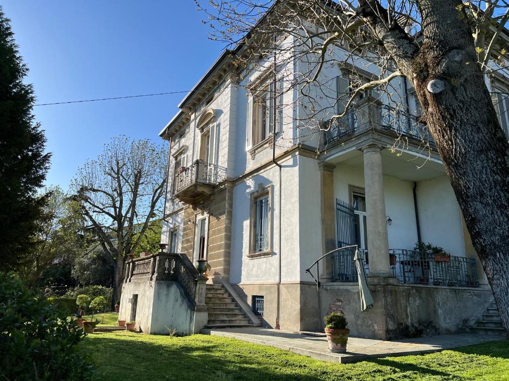 a large white house with a balcony and a tree at Villa Rosazza in San Salvatore Monferrato