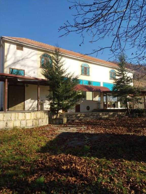a white building with a tree in front of it at İsmayıllı bağ evi in İkinci Yeniyol