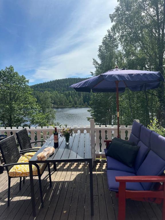 a patio with a blue couch and an umbrella at hytte ved innsjø in Skien