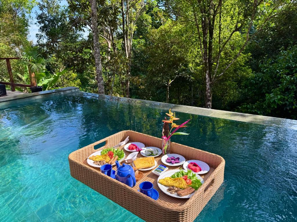 a tray of food on a table next to a swimming pool at AVYANA sanctuary in Gobleg