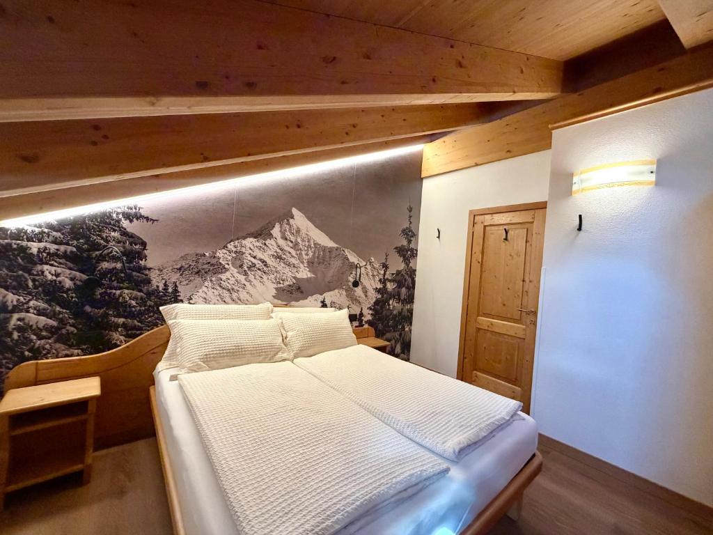 a bedroom with a bed with a painting on the wall at Rosengarden Alpine Residence in Valdidentro