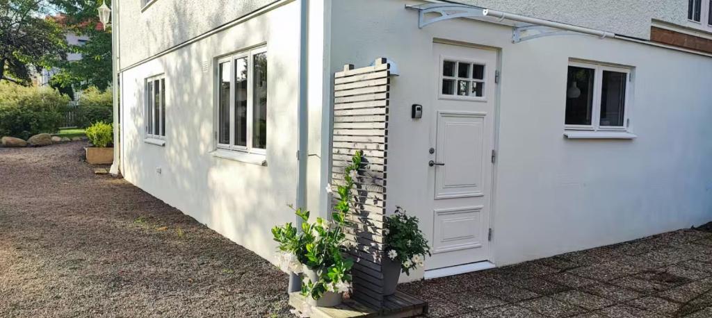 a white house with a door and a plant at Apartment Sollid - Your comfortable accommodation in Huskvarna