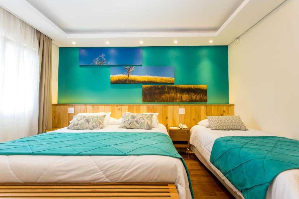 2 camas num quarto com uma parede verde em Hotel Serra da Estrela em Campos de Jordão