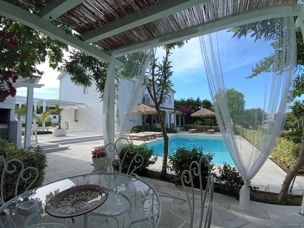 a patio with a glass table and chairs and a swimming pool at Tenuta viale degli ulivi in San Martino in Pensilis