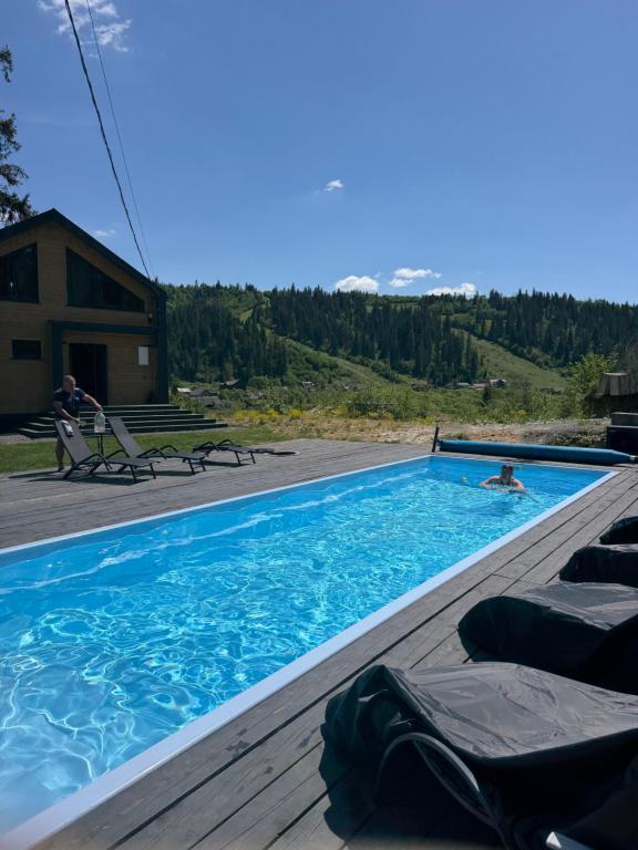 a swimming pool with lounge chairs on a wooden deck at Luxury Home in Slavske
