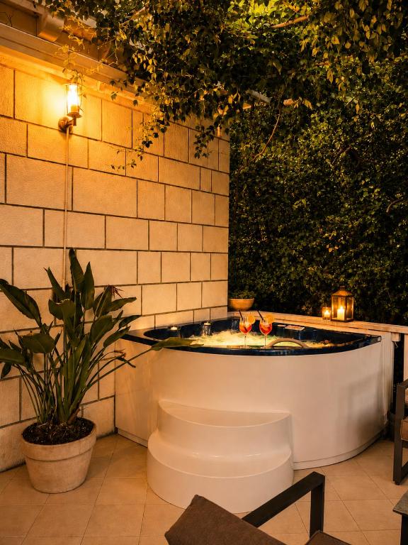 a bathtub in a patio with a plant and lights at Frenchie suite in Lopud