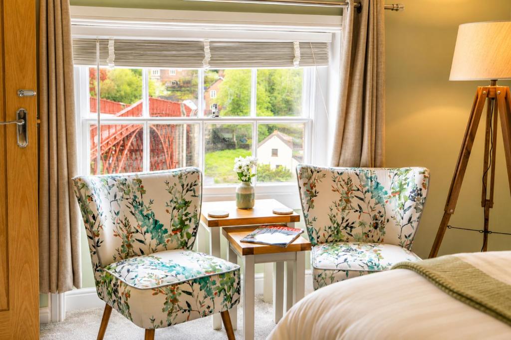 a bedroom with two chairs and a table and a window at Bridgeside Rooms in Ironbridge