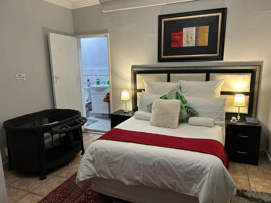 a bedroom with a large bed and a chair at The Family Room in Krugersdorp