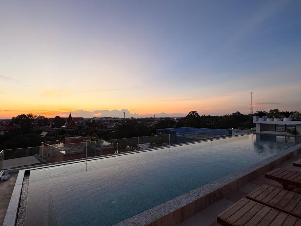 a large swimming pool on top of a building with a sunset at Sonitori Riverside in Siem Reap