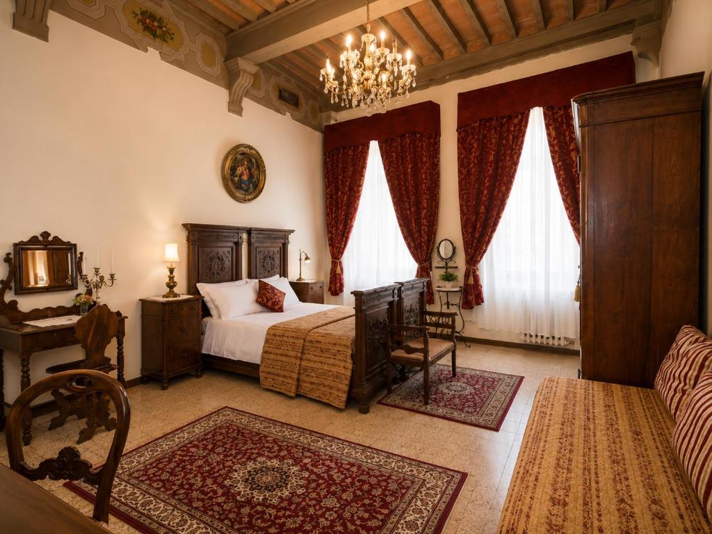 a bedroom with a bed and a chair and a table at All'Ombra della Torre a due passi da Piazza del Campo in Siena