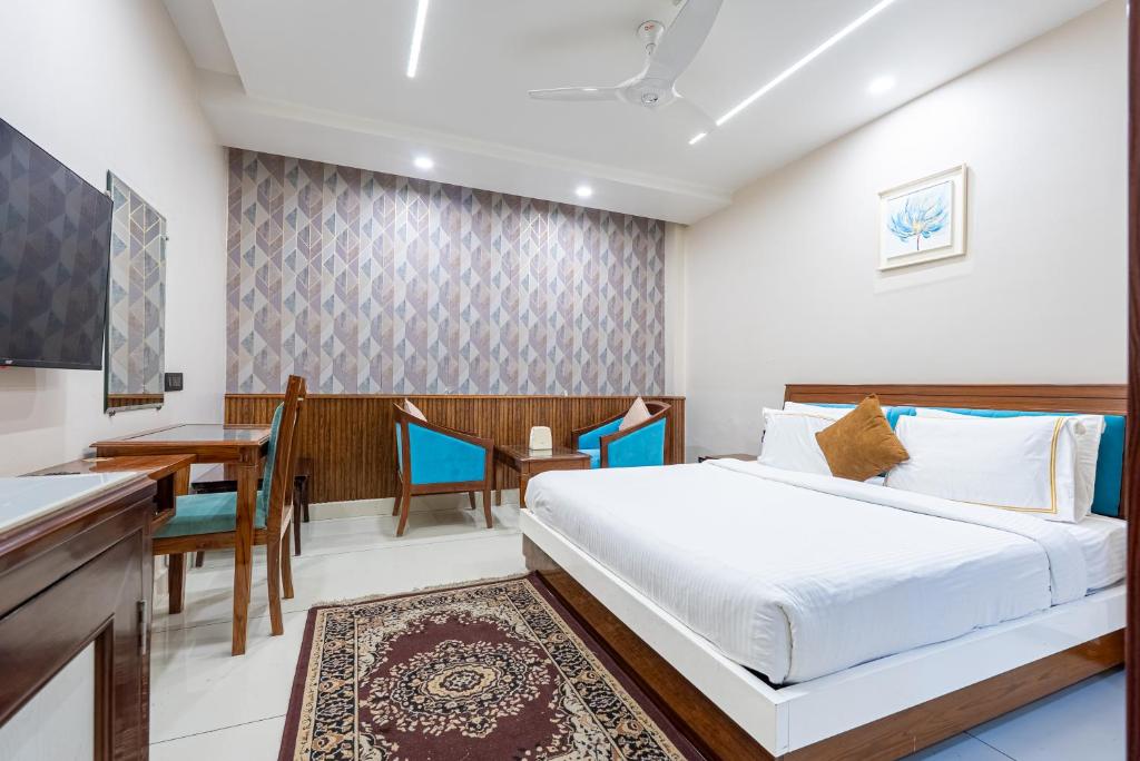 a bedroom with a bed and a table and a desk at Hotel Leela Grande in Karnāl