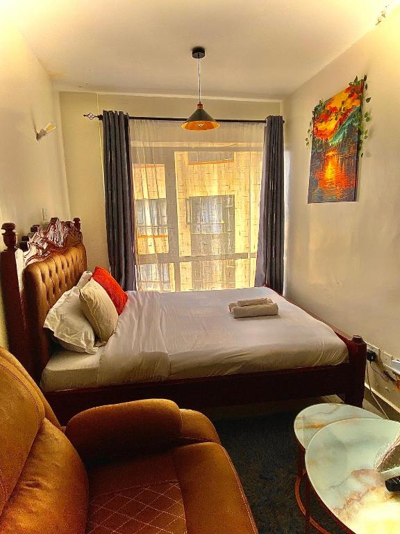 a bedroom with a bed and a couch and a window at Tripstar villa studio at Tsavo sunset Kiambu Road Thindigua in Kiambu