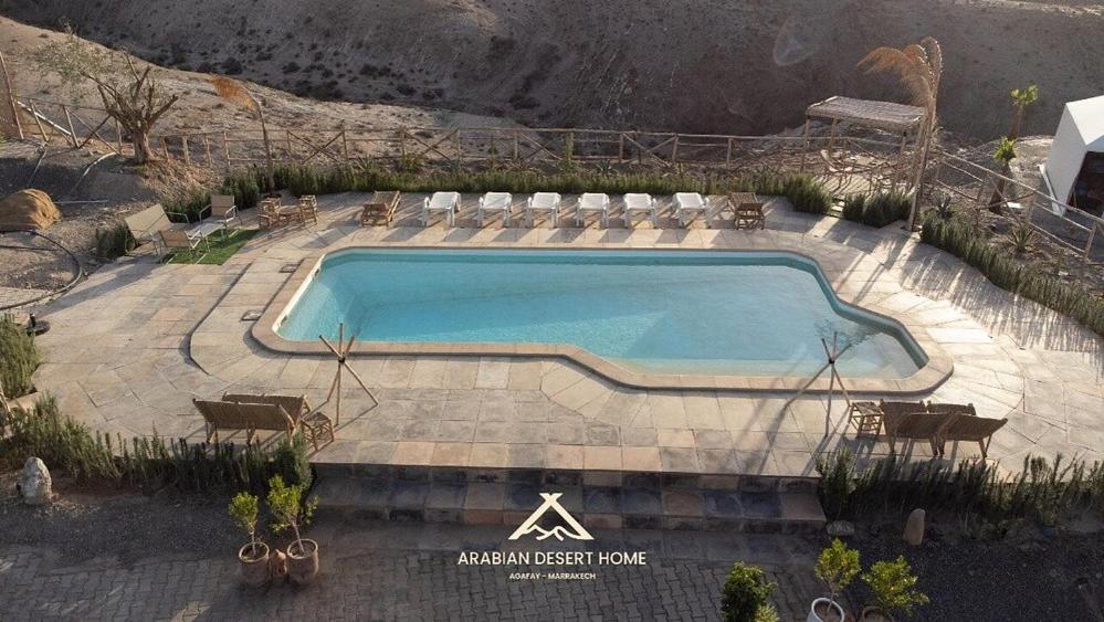 a large swimming pool with chairs at Arabian Desert Home in Aït Mazou