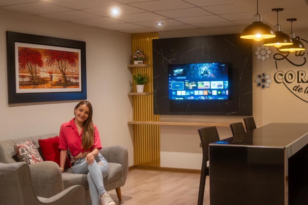 a woman sitting in a waiting room with a tv at Apartamentos WANCA SUITES para 4, 5 y 6 huéspedes cochera muy cerca al Centro in Huancayo