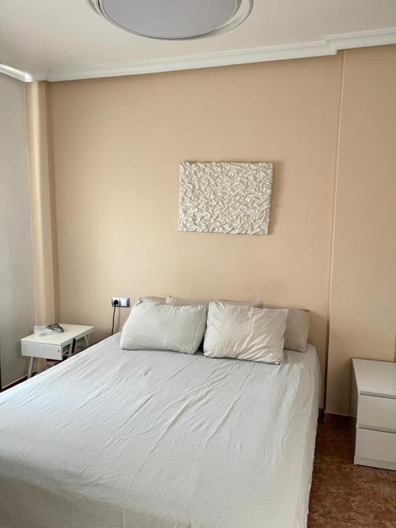 a bedroom with a white bed with a painting on the wall at B&B Guale in Gualeguaychú