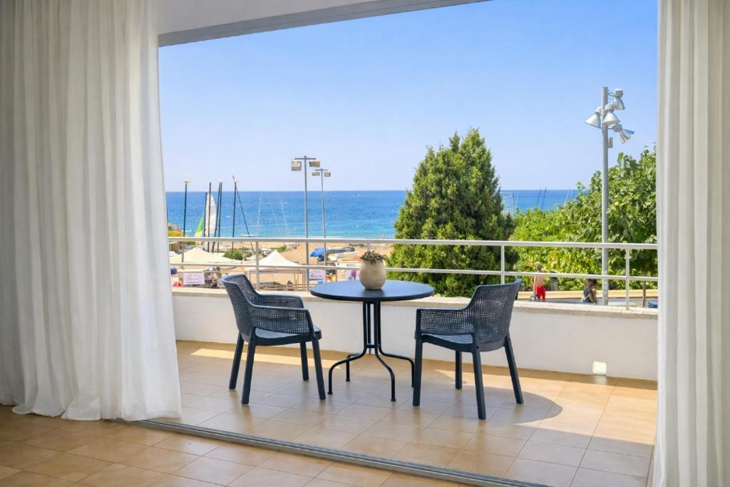 a table and chairs in a balcony with a view of the ocean at La Casa de la Punta in San Pol de Mar