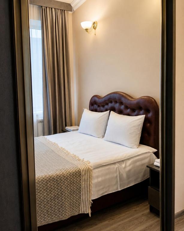 a bedroom with a bed with white sheets and a mirror at Mina Hotel in Goris