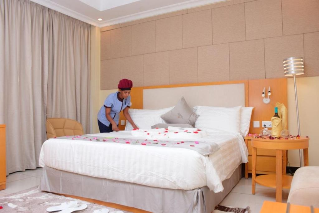 a man making a large bed in a hotel room at Diamond Luxury Hotel plc in Desē