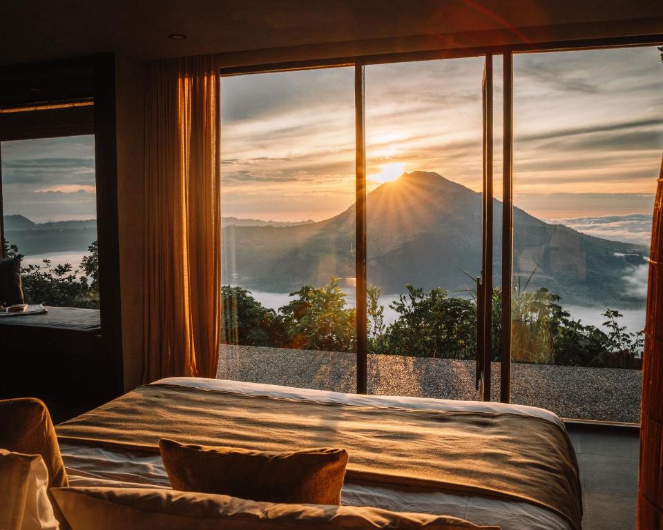 a bedroom with a large window with a view of a mountain at Batur Cabins in Kintamani