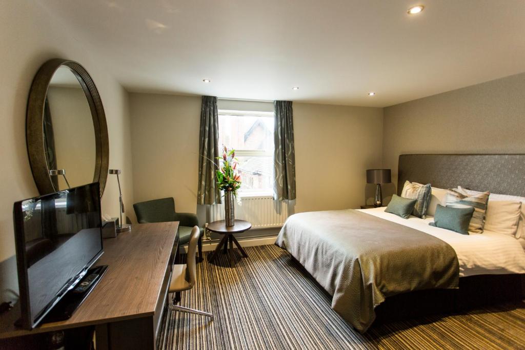 a hotel room with a bed and a flat screen tv at Woodland Grange in Leamington Spa