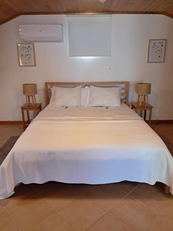 a bedroom with a large white bed with two chairs at Casa Vida Alegre in Prazeres