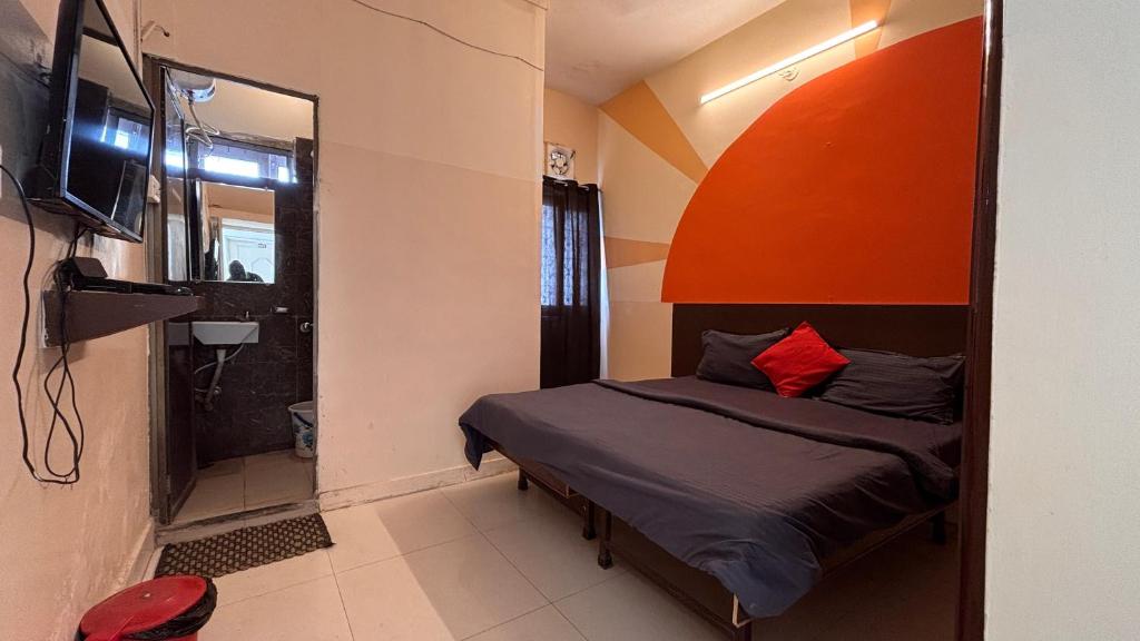 a small bedroom with a bed with an orange headboard at Preet Residency Homestays in Jabalpur
