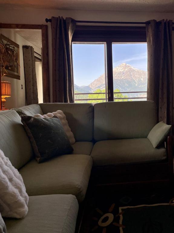a living room with a couch and a large window at Central Spacious Apartment, Mountain Views in Sauze d'Oulx