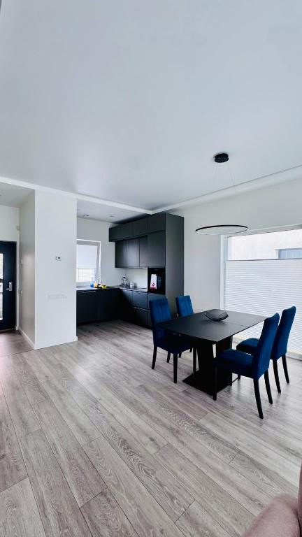 a dining room with a black table and blue chairs at Ungura Nord in Mozūriškiai