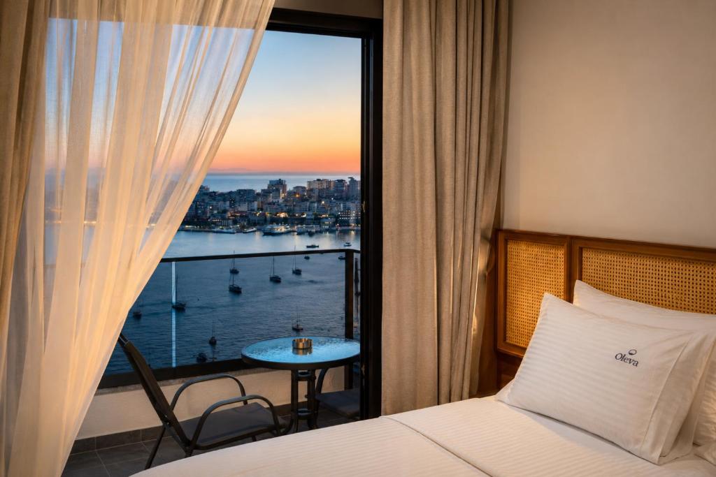 a hotel room with a bed and a view of the water at Oleva Sea View Suites in Sarandë