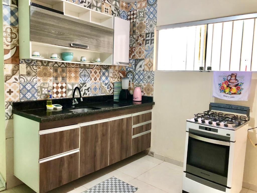 a small kitchen with a stove and a sink at Casa três quartos em condomínio in Garanhuns